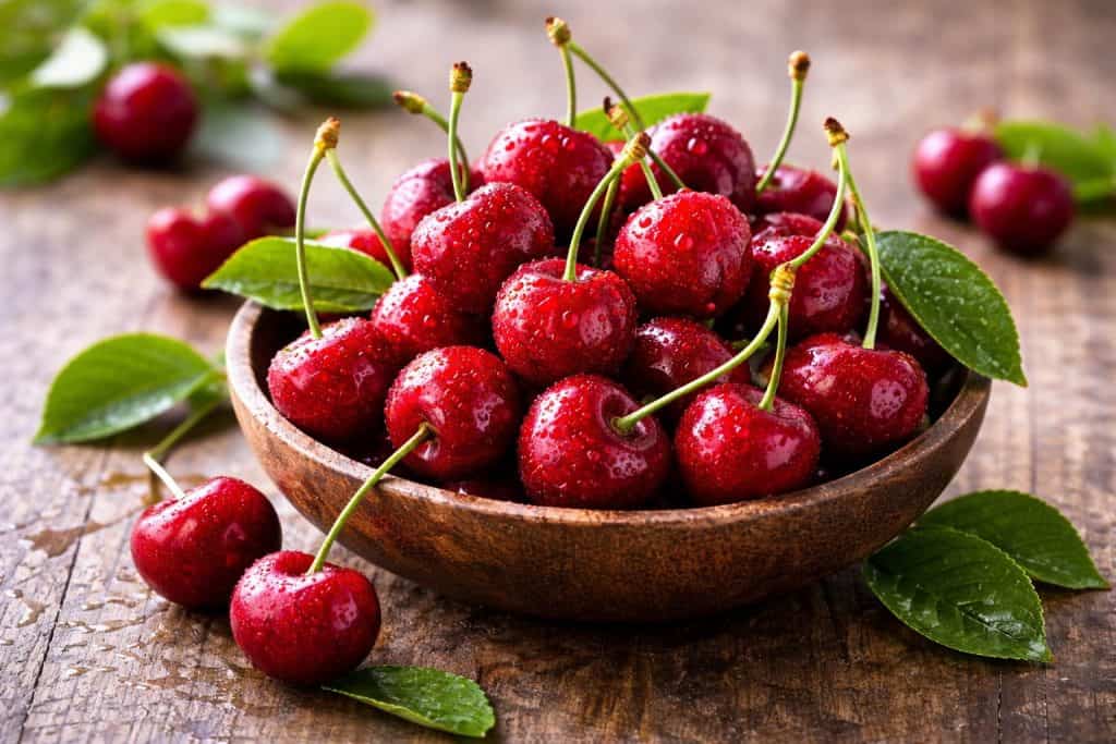 Landscape image of a bowl filled with ripe red cherries, representing cherry flavoured e-liquid.